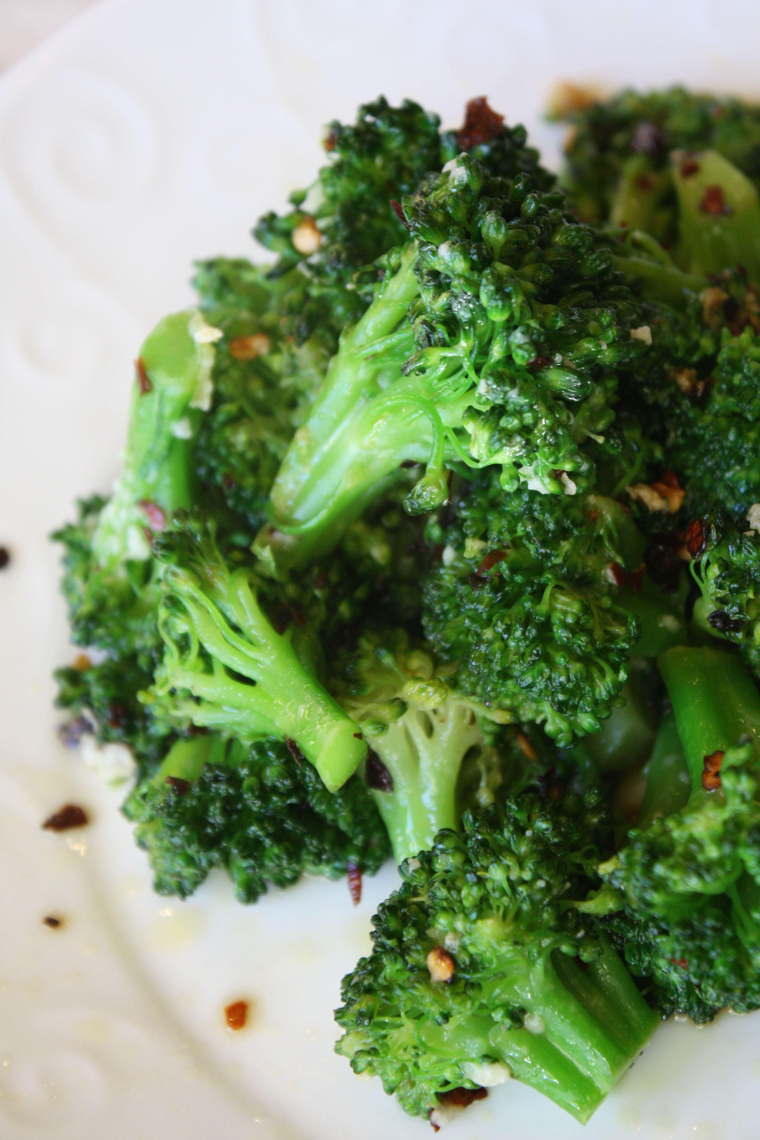 a plate full of bright green and crisp tender sauteed broccoli with garlic and red pepper