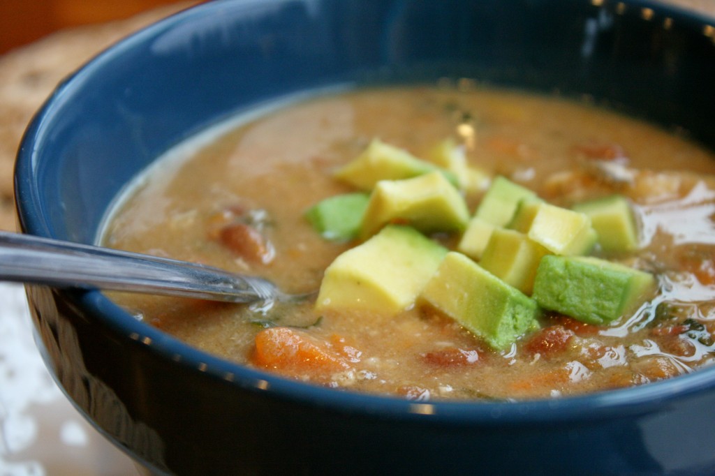 a closeup of a dark blue bowl filled with thick and creamy pinto bean and sweet potato stew