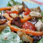 a up close view of a blt salad with a creamy mayo dressing, bacon, tomato, and crispy chicken thighs