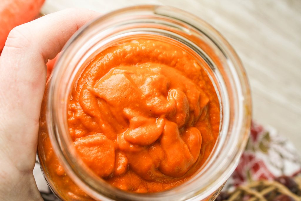 overhead closeup of a birght orgage red roasted tomato sauce in a mason jar