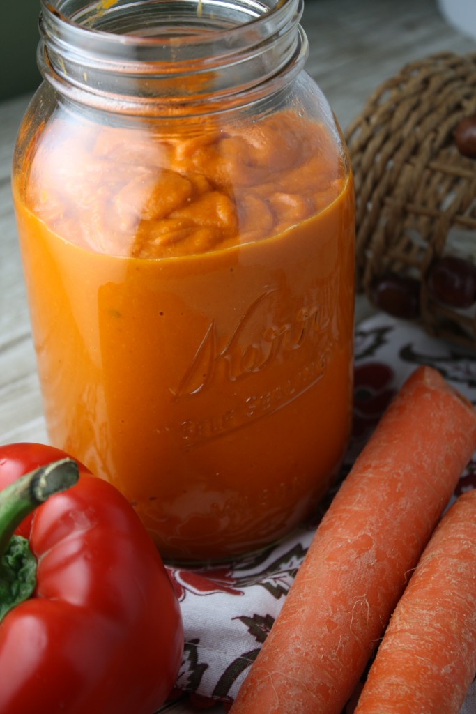 vertical image of a quart sized glass mason jar filled with roasted tomato sauce with a fresh pepper and carrot