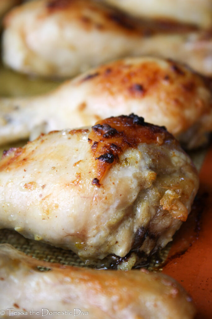 eye level close up of of a crispy skinned chicken drumstick on a non-stick baking mat