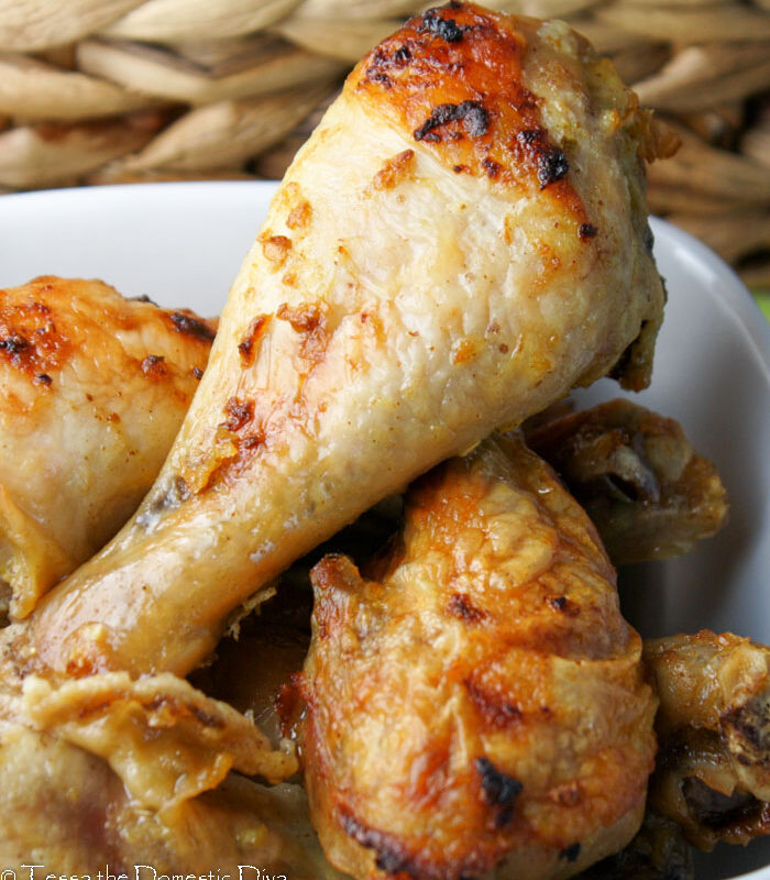 three chicken drumsticks arranged in a white bowl with a crispy skin