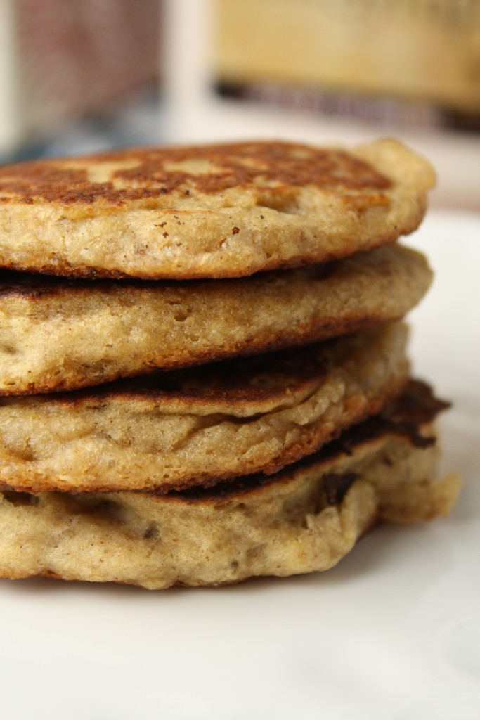 4 stacked golden brown pancakes on a white plate