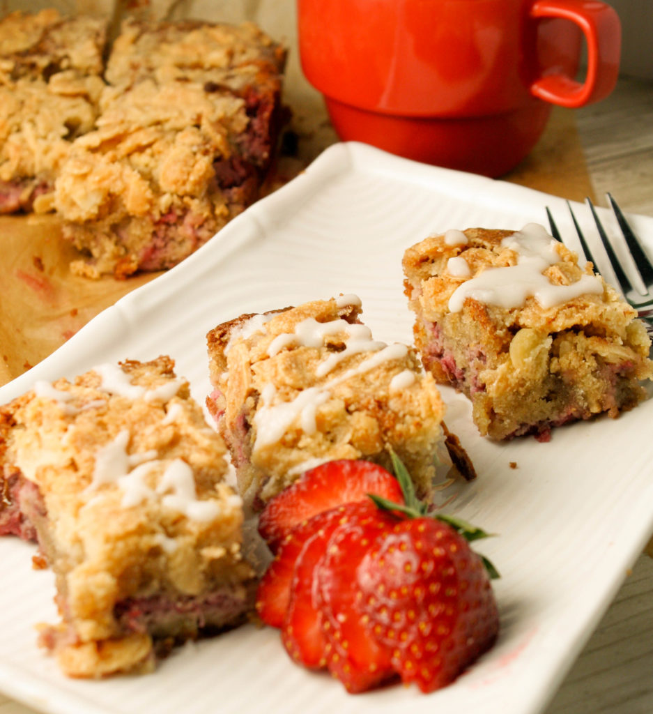 3 slices of strawberry almond coffee cake on a white plate with fresh cut berries