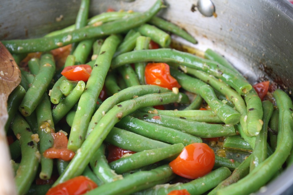 fresh green beans with cherry tomatoes and basil in a stainless steel cooking pan