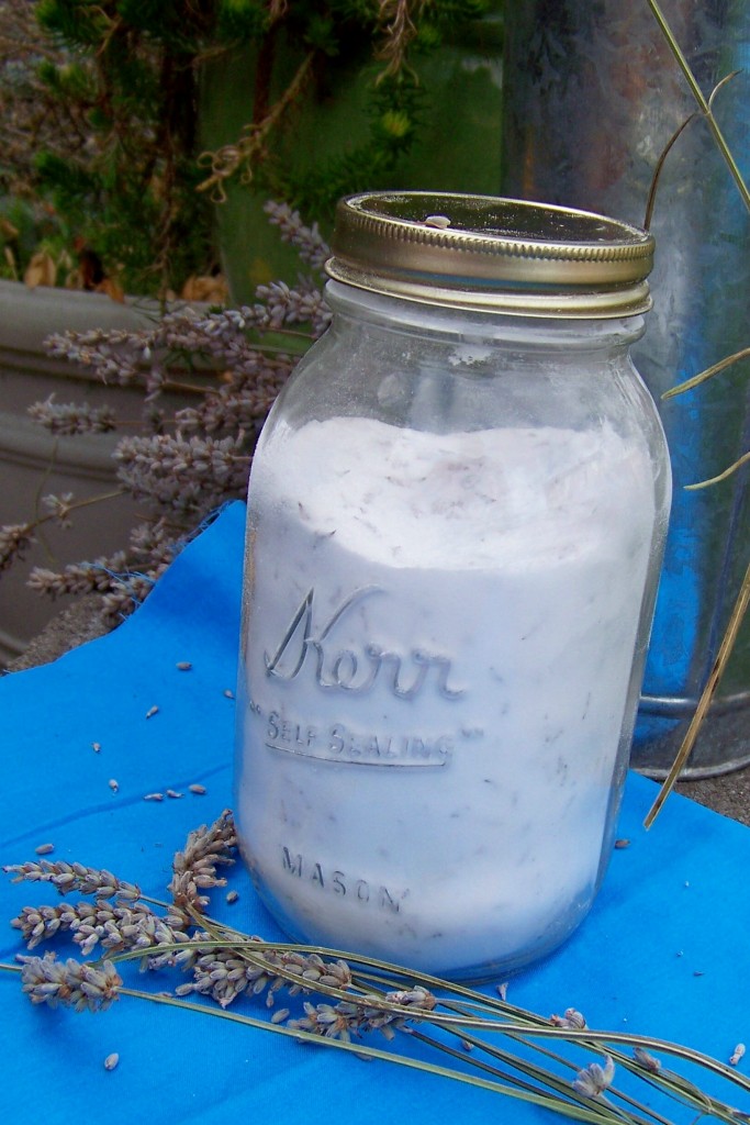 quart size mason jar filled with white baking soda and dried lavender flowers on a vibrant blue clothe with a scattering of dried lavender flower stalks