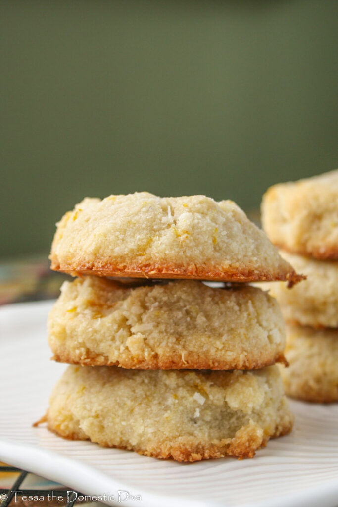 three almond flour orange cookies stacked with green background at eye level