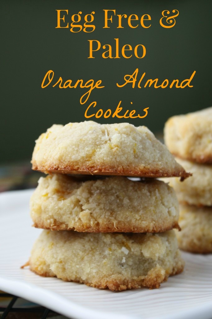 optimized for pinterest three stacked orange almond cookies with golden bottoms with a dark green backdrop