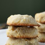 three almond flour orange cookies stacked with green background at eye level