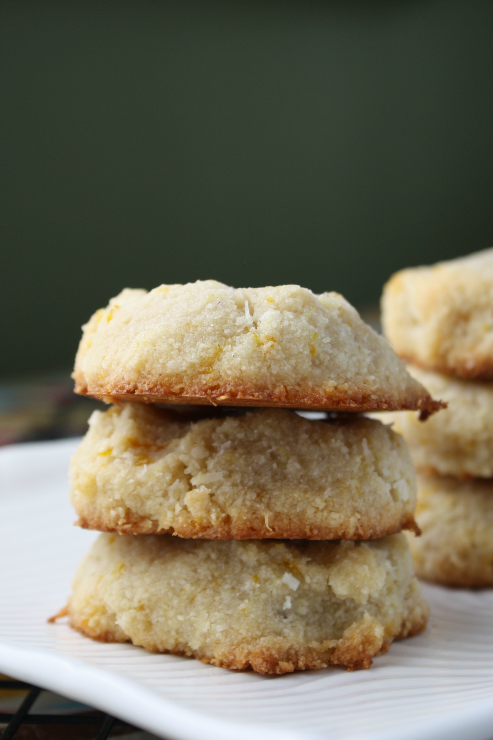 three almond flour orange cookies stacked with green background at eye level