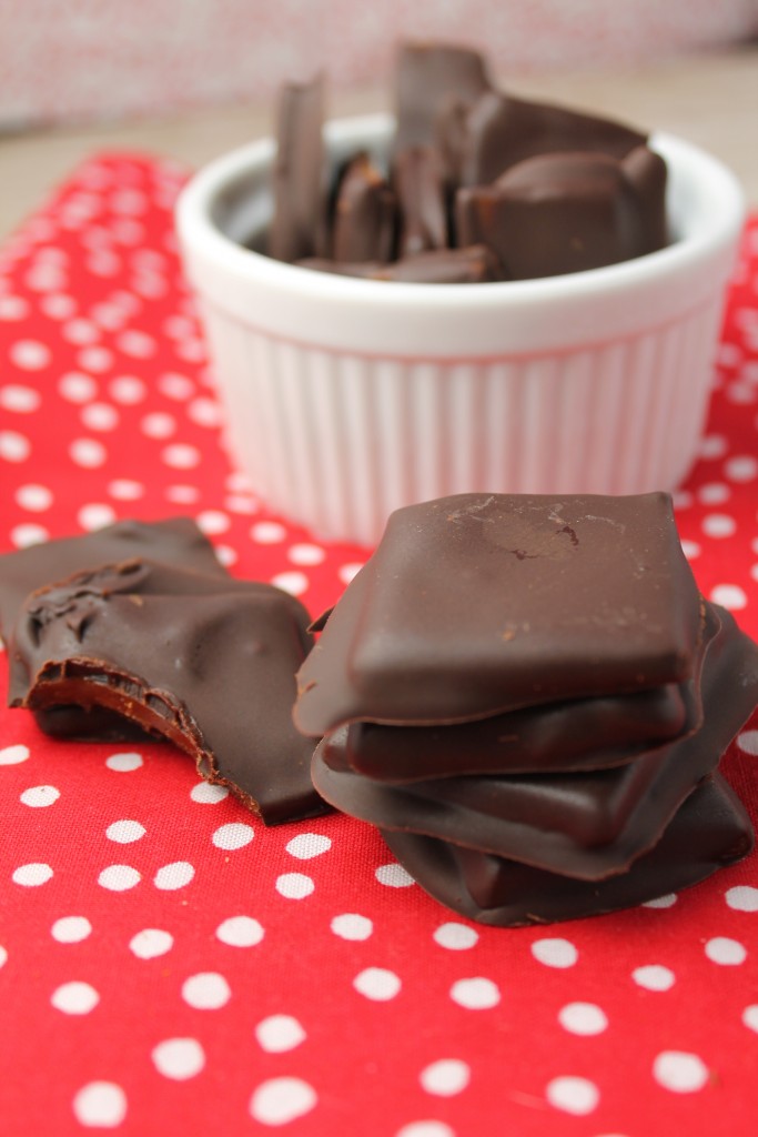 chocolate dipped paleo toffee squares arranged on a red and white polka-dot cloth with a white ramekin
