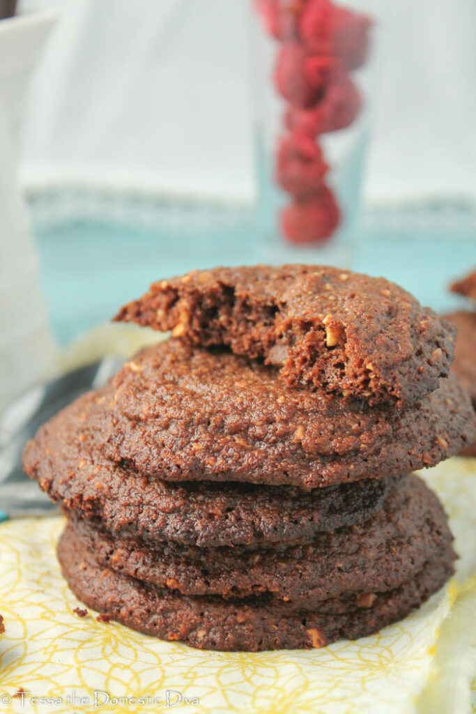 several stacked chocolate hazelnut cookies with a cup of red berries in the background