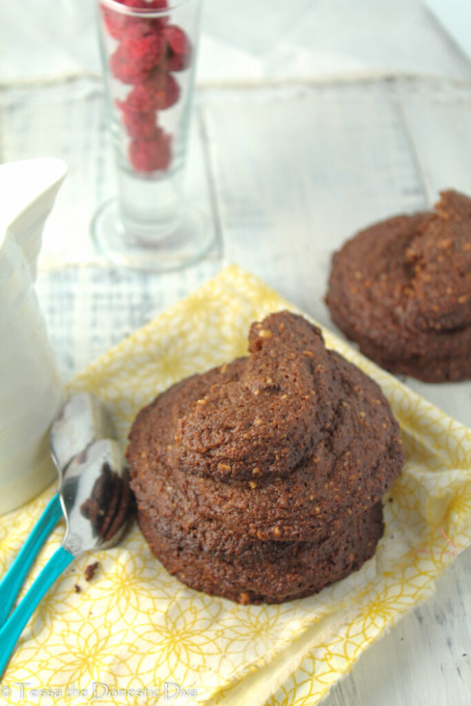 an arrangement of paleo chocolate cookies with hazelnuts and some fresh berries on a yellow cloth