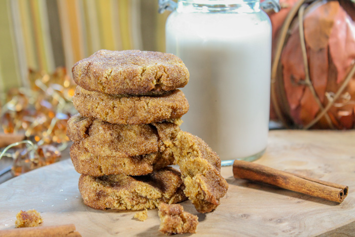 cinnamon and sugar crusted pumpkin cookies in a stack with a cinnamon stick and glass of milk