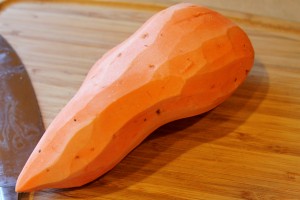 peeled sweet potato on a wooden cutting board