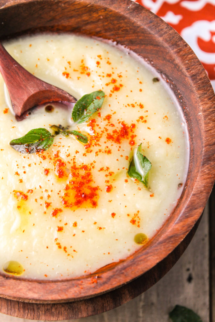 birdseye view of a thick and creamy white soup with droplets of olive oil and fried oregano