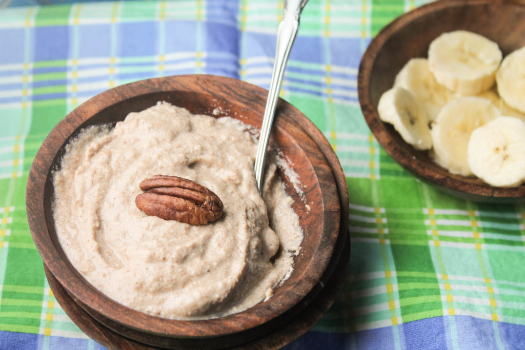 creamy paleo porridge topped with a whole pecan and sliced bananas in the back