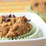 eye level close up of a cocoa nib topped banana muffin in green paper liners.