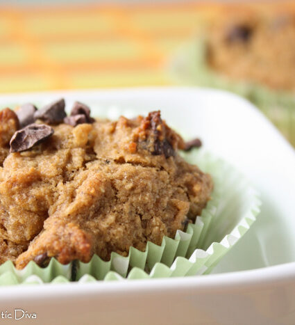 eye level close up of a cocoa nib topped banana muffin in green paper liners.