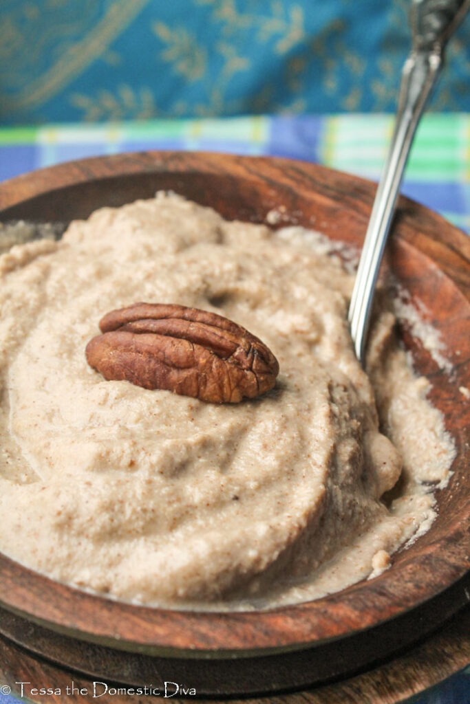 wooden bowl of maple nut porridge with banana and a pecan half