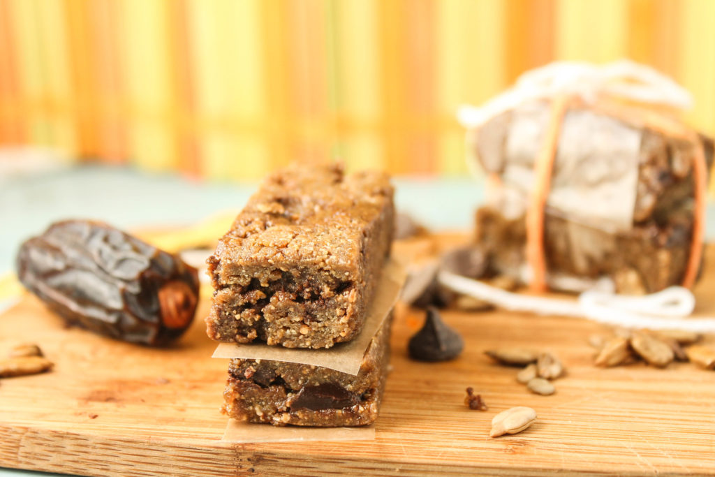 horizontal image of sunflower seed and date bar rectangles on a wooden cutting board with some roasted sunflower seeds and dates scattered around