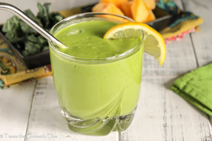 a clear class with a thick and creamy green smoothie with mango and lemon and coconut