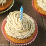 overhead shot of swirled vanilla speckeled frosted cupcake with a birthday candle