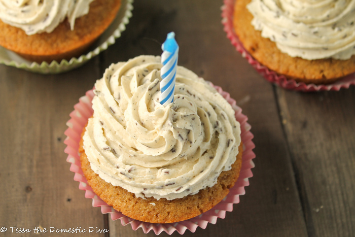 overhead shot of swirled vanilla speckeled frosted cupcake with a birthday candle