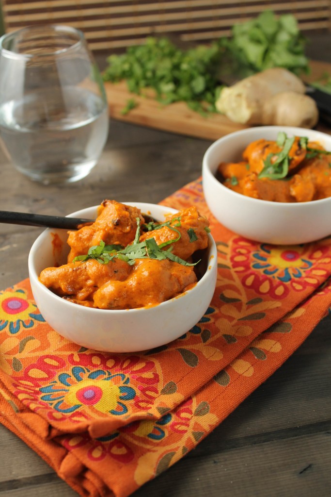 two white bowls filled with chicken tikka masala on an orange paisley cloth