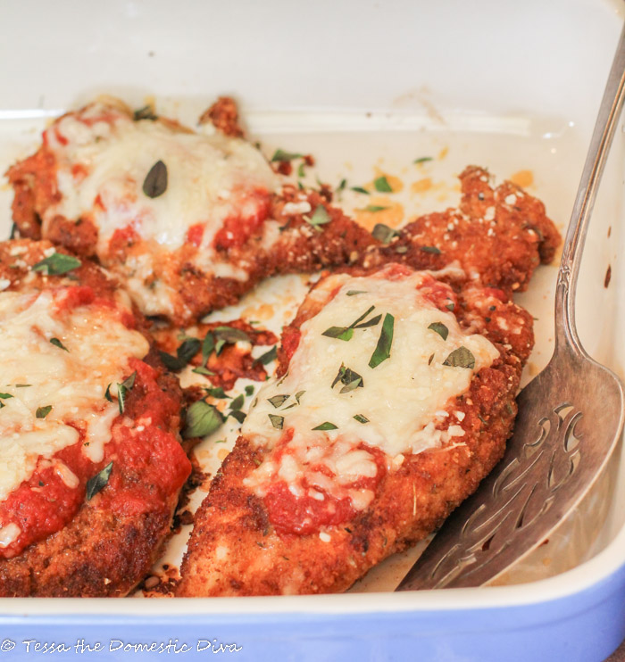 chicken parmesan no egg in blue ceramic baking dish with tomatoe sauce and melted cheese