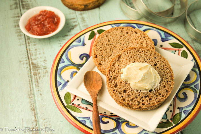 a overhead view of a a plate of a halved teff English muffin with fresh preserves and a pat of butter