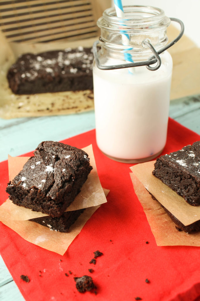 several squares of stacked chocolate brownies with a glass of milk.
