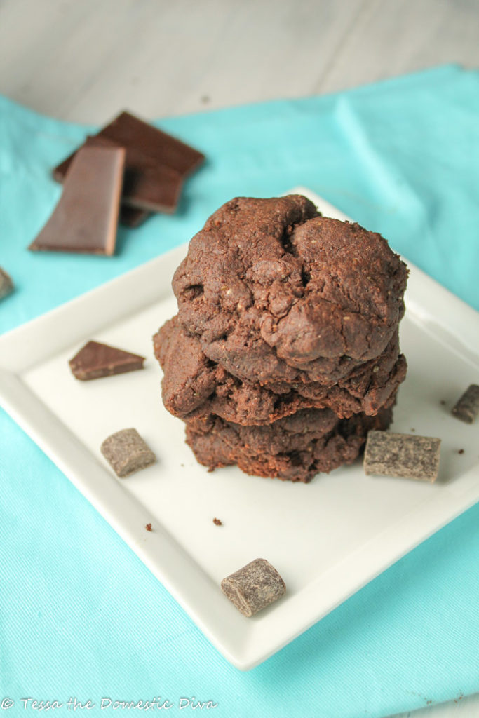 birdseye view of a stack of double chocolat chip cookies on a white plate atop a turquoise linen