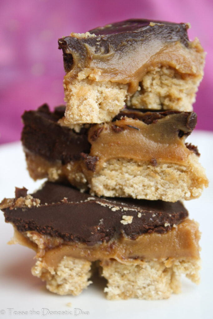 three triangles of a shortbread crust topped with creamy peanut butter and chocolate