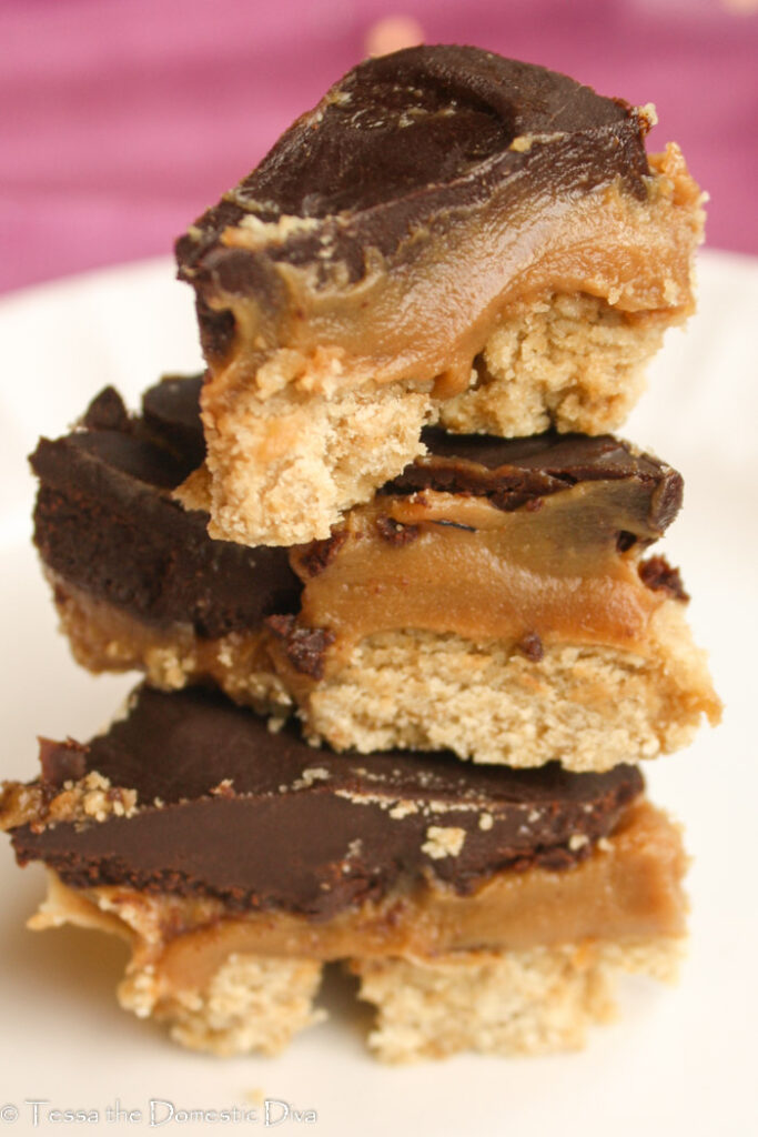a stack of three creamy peanut butter bars with a shortbread crust and chocolate topping