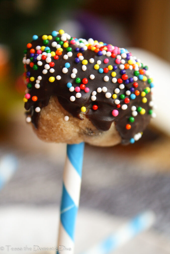 chocolate covered cookie dough ball  on a white and blue striped paper straw with sprinkles