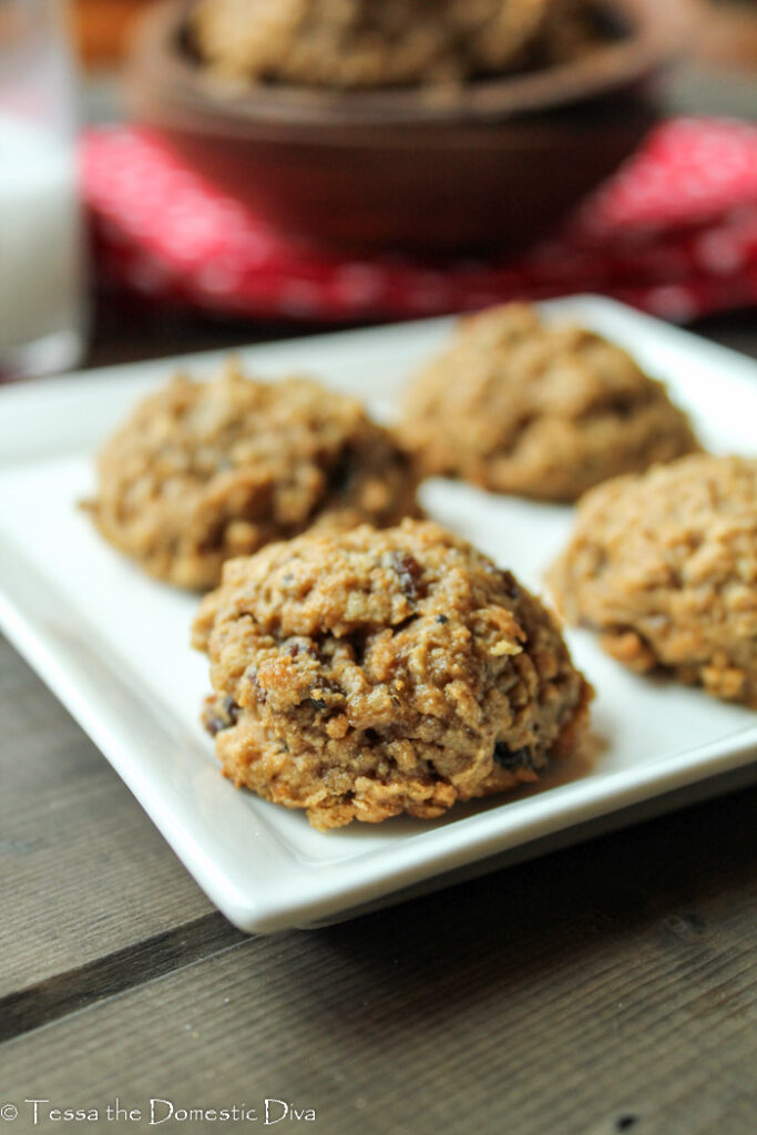 eye level image of 4 oatmeal cookies on a square white plate with raisins and a red cloth