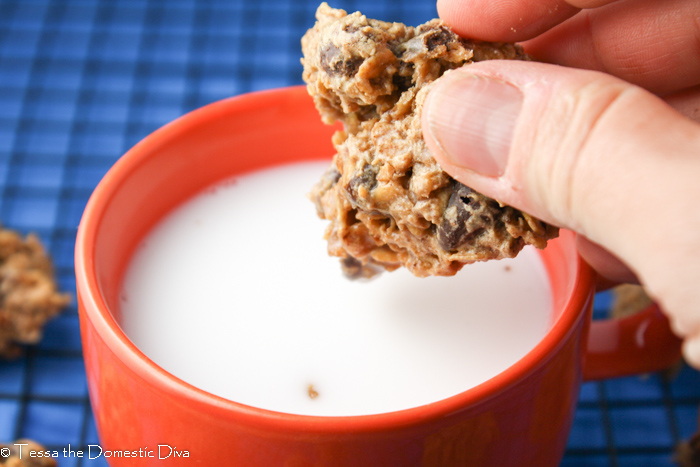 a oatmeal cookie held over a mug of dairy free milk