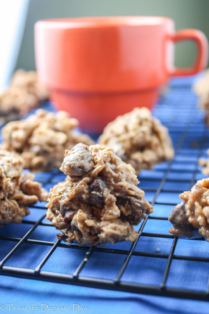 oatmeal chocolate cookies arranged on a cooling rack with a red mug and royal blue linen