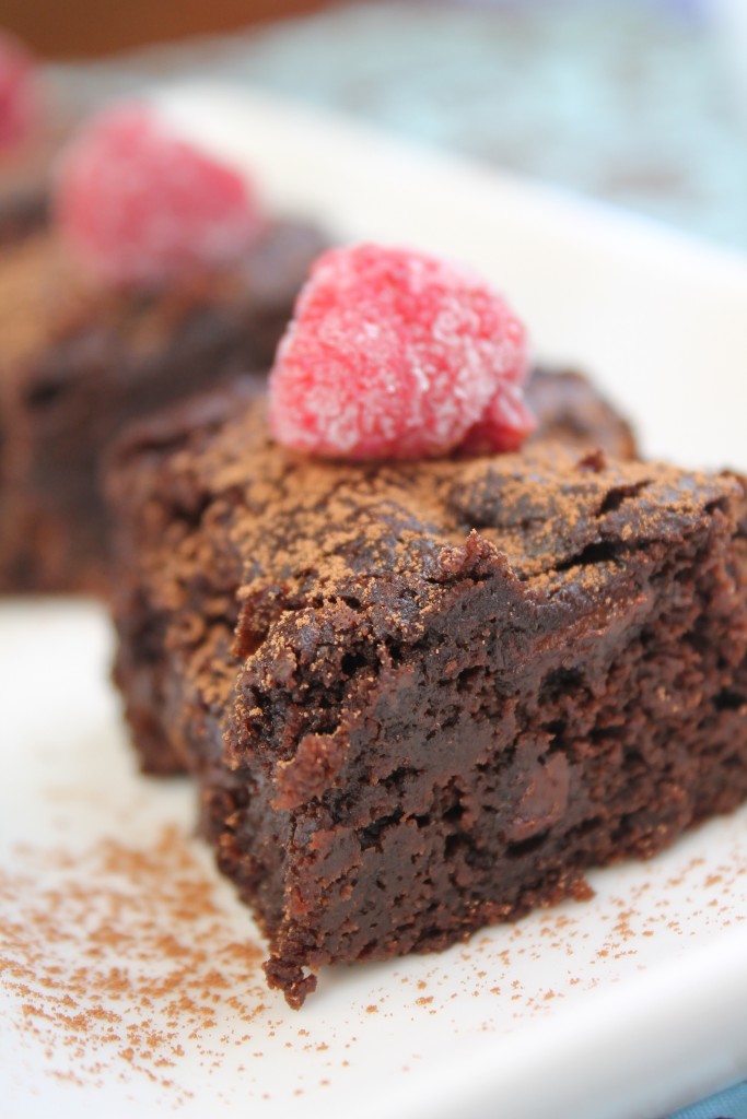 a cocoa dusted square of chocolate cake with a frozen raspberry on top