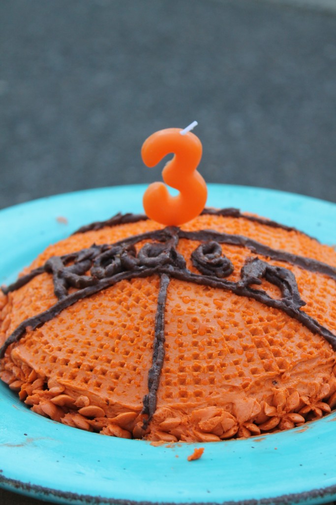 a basketball children's birthday cake with a number 3 candle on top