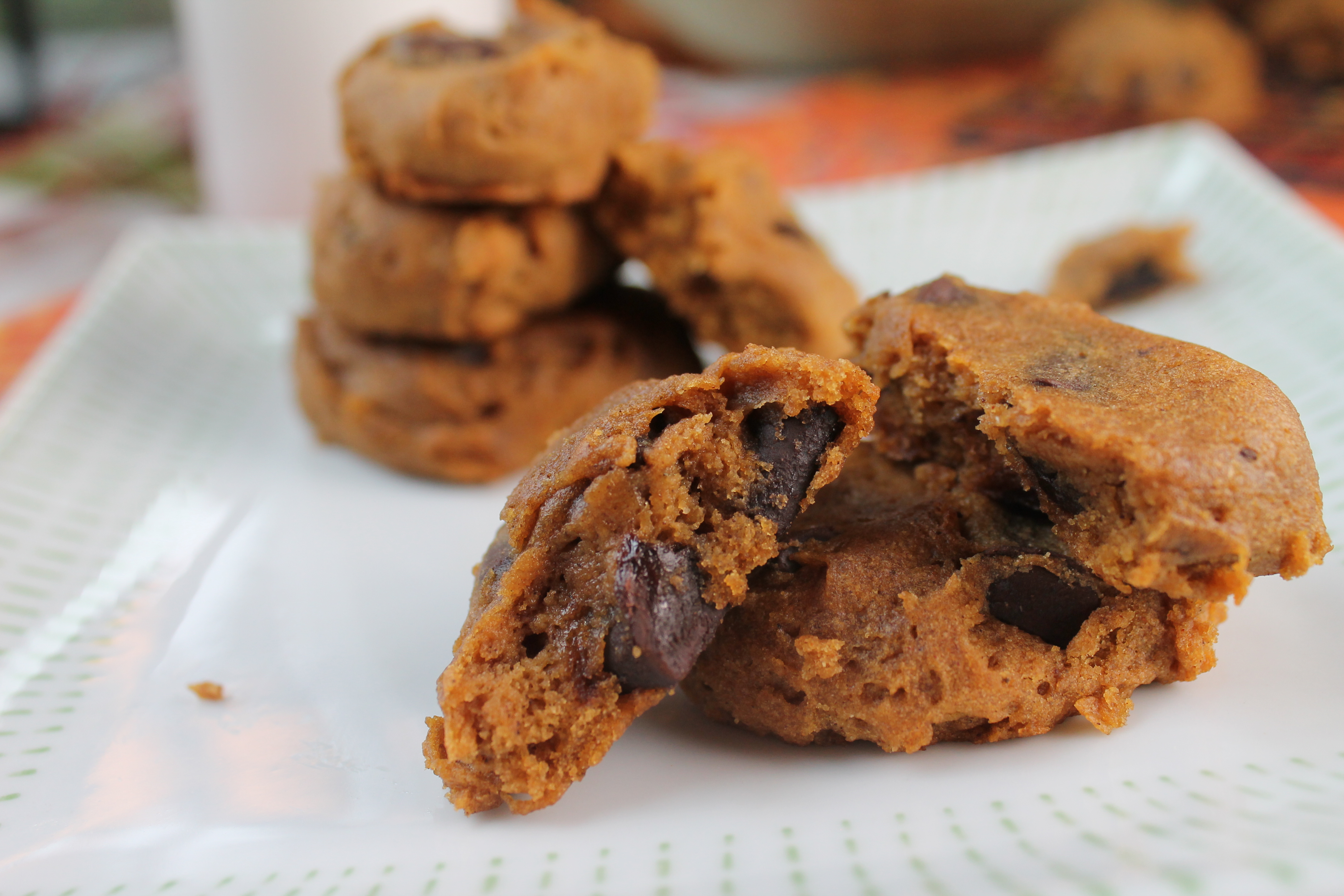 horizontal image from eye level of a white plate stacked with soft pumpkin cookies loaded with chocolate chips