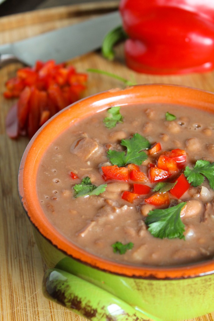 front eye level view of a green ceramic bowl filled with creamy pinto beans in broth