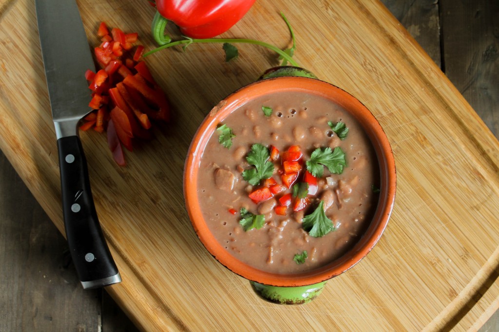 horizontal image of a bowl of pressure cooker pinto beans from above on a wooden bamboo cutting board