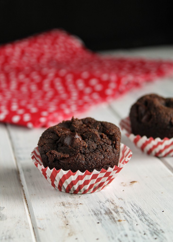 chocolate muffins studded with chocolate chips in a white and red striped paper muffin liner
