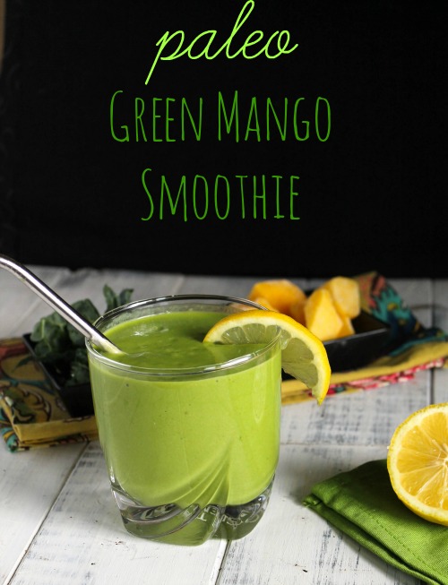 optimized for pinterest bright green smoothie in a clear glass with a lemon slice and mango chunks in the background