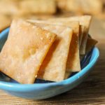 7 golden crispy gluten free crackers arranged in a turquoise blue dish