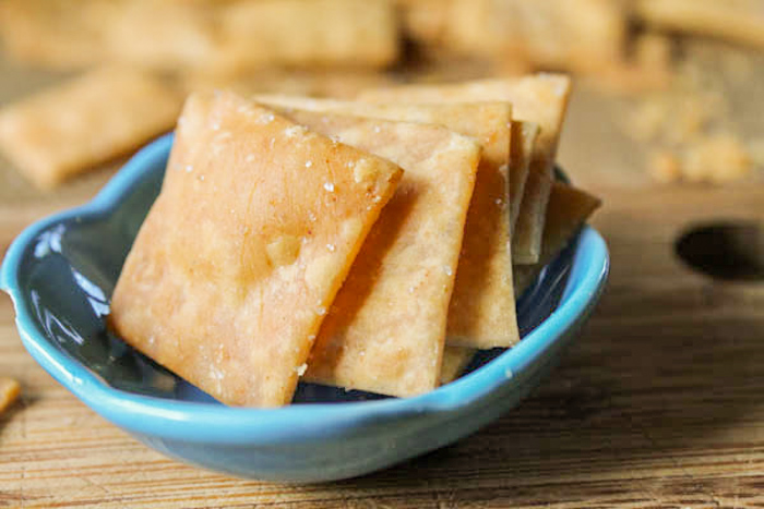 7 golden crispy gluten free crackers arranged in a turquoise blue dish