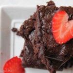 birds eye close up of a stack of cocoa powder brownies with a slice of strawberry in a heart shape on top